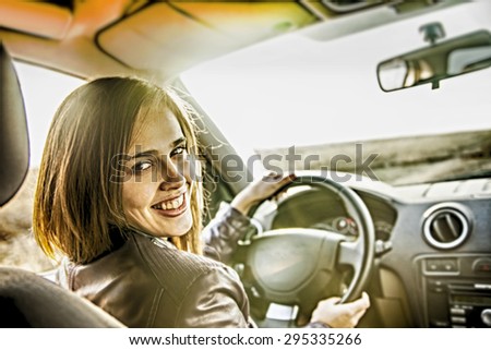 woman in car indoor keeps wheel turning around smiling looking at passengers in back seat