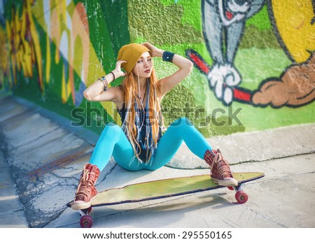 Full length Portrait of Beautiful redhead caucasian teen girl with long skate board stand against graffiti style wall. Outdoors, urban lifestyle. Empty space for inscription. Youth subculture