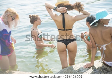 Side view of young girls bottom in bikini Group of young adult Woman Fitness Pleasure Team of sexy very hot wet female enjoy beach party Tanned skin Lady resting and talking with smiley faces