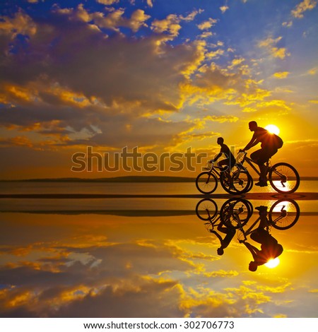 Empty Space Sporty friends on bicycle on sunset Silhouette couple cyclist go along shoreline coast Sport in Nature background Group of people two mountain biker in sunrise with reflection sun in water