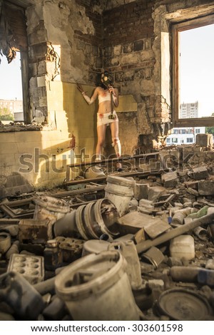 Full length Woman with gas mask in a grunge background Post apocalypse girl stand in angle abandoned dirty yellow wall with shadow from sun light Toxic trash in dusk room Window frame lie on floor