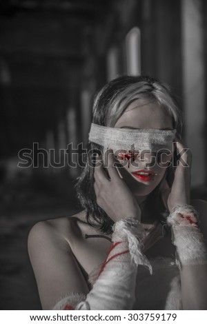 Girl stigmata. Blind sexy woman in bloody bandage. The nails driven into the hands Female stand inside dark room with windows in perspective Empty space for inscription