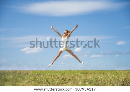 Alone blond Woman Jumping for Joy on a Grass Hill above horizon line One happy slim girl fly in a green field against blue summer sky with clouds Idea of success, growth , light, diet, luck, freedom