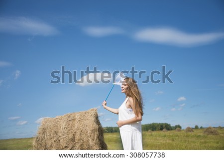 Portrait of happy young adult girl with scoop-net in sunny field with fresh green grass Cute caucasian woman against blue sky with clouds Empty space for inscription Sunny day