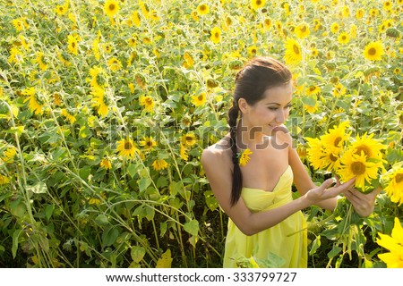 portrait of young adult beautiful joyful latin hispanic woman with long brunette hair wearing yellow dress in sunflower field girl inhales aroma of wild flowers Copy space for inscription