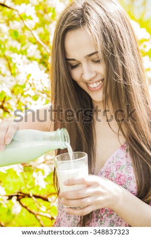 Portrait young adult latin hispanic girl in day light summer white orange dress with polka dots deep neckline Woman hold in hand glass bottle milk in faceted cup Female enjoy taste of childhood