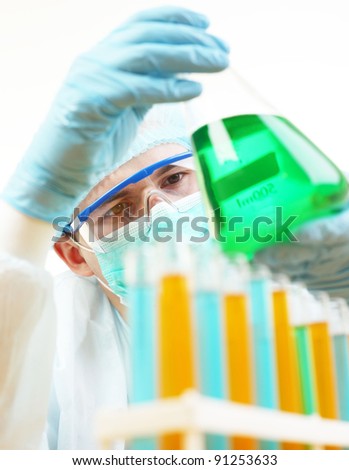 chemist looks at the liquid in the flask  Young clinician making experiment with green water in laboratory