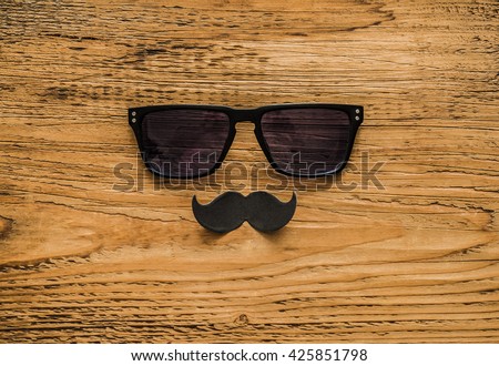 Happy fathers day sticker, wooden glasses, black paper mustache on wooden background
