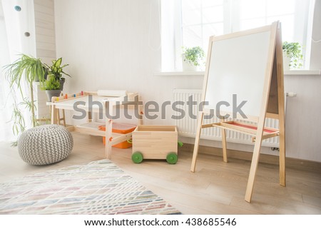 Kindergarten room with easel chair and table for painting. children\'s room and furniture and natural green  flowers on white windowsill