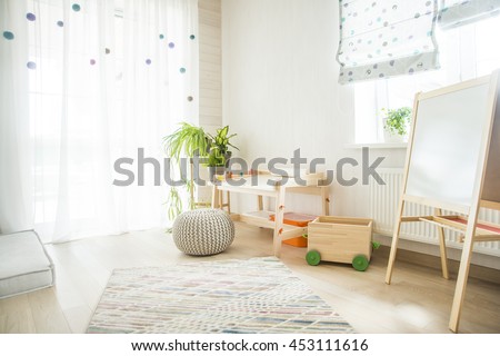 Kindergarten room with easel chair and table for painting. children\'s room and furniture and natural green flowers on white windowsill