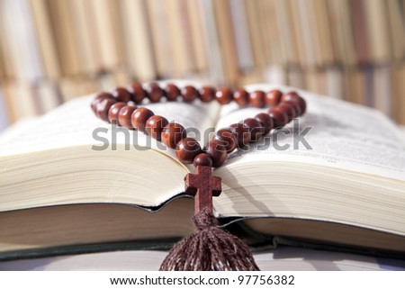 Russian bible and wooden rosary on the background of the library bookshelves