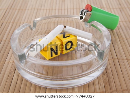 the word - no, or include the yellow cubes in clear glass ashtrays on gray background - concept ban smoking in public places and anti-smoking bad habit