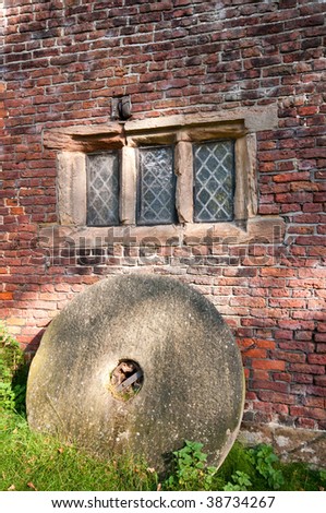 Mill stone against mill wall under window
