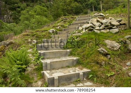 Set of steps going up a hill side with pile of rocks.