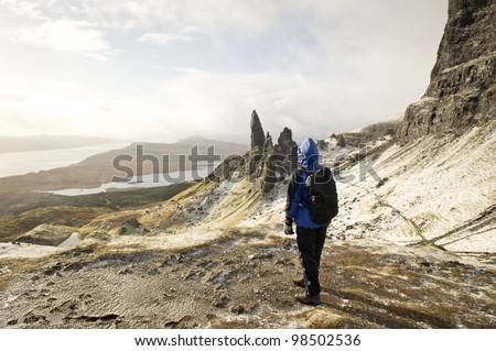 Woman walker hiker standing looking at the Old Man Of Storr on the Isle Of Skye Scotland