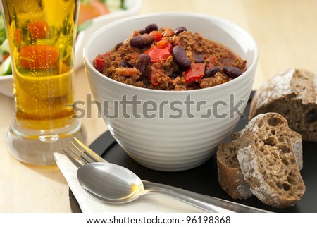 Hot and spicy minced meat chili with fresh bread and cold beer