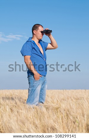 Man with field-glass in hand on wheat field