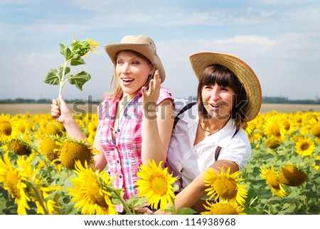 Two beautiful girls in cowboy hats at the sunflowers field. Country fashion style.