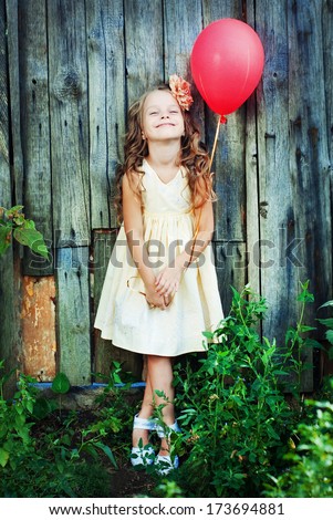 Happy Child in Summer.  Beautiful Girl with Red Balloon in the Garden. Happy Children. Healthy Kids. Spring Time. Vacation in the Countryside.