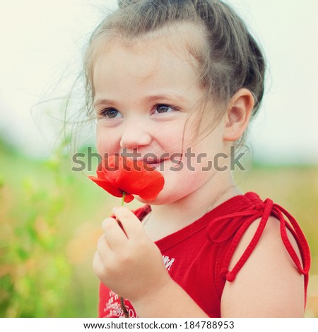 Happy cute child girl with poppy flower. Happy kid outdoor. Healthy lifestyle