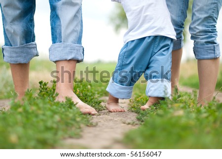 Happy Family on a Walk in Summer. Child with Parents Together. Feet Barefoot on Green Grass. Healthy Lifestyle. Dad Mom and Son. Spring Time