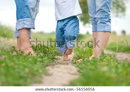 Happy Family on a Walk in Summer. Child with Parents Together. Feet Barefoot on Green Grass. Healthy Lifestyle. Dad Mom and Son. Spring Time