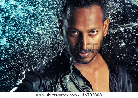 Water splash on smart Indian young man.