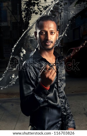 Water splash on smart Indian young man.