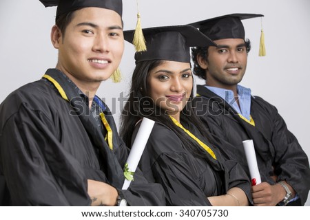 Group of Indian college graduates wearing cap and gown holding diploma on white background