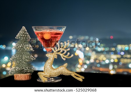 festive celebration background and texture ,a glass of  cocktail, decoration of reindeer and bottle of red wine on dark stone table blurred bokeh background,