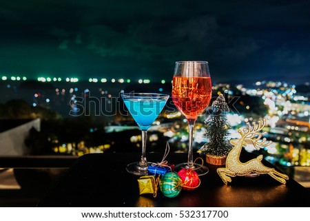 festive celebration background and texture ,two of cocktail of glass, blue margarita and rose wine with decoration of reindeer and  bottle of red wine on dark stone table blurred bokeh background,