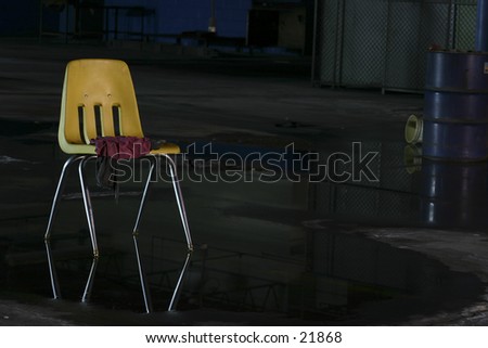 Yellow chair stands boldly against dark, wet abandoned factory.