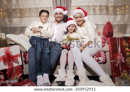 Family on a sofa among a large number of gifts. Festive time of joy and love. Family time.