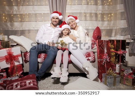 Family on a sofa among a large number of gifts. Festive time of joy and love. Family time.