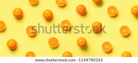 Fruit pattern of fresh orange slices on yellow background. Top view. Copy Space. Pop art design, creative summer concept. Half of citrus in minimal flat lay style. Banner