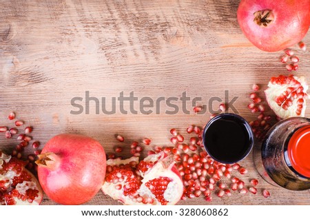 Glass of fresh pomegranate juice, pomegranate seeds and fruits on wooden background. Food frame. Free space for text