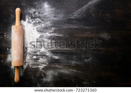 Baking background with free space for your text. Rolling pin and flour on black table. Copy space. Top view