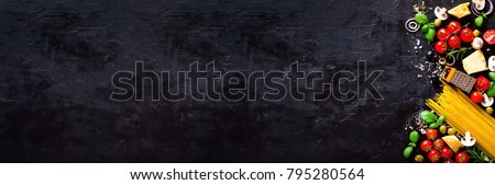 Food ingredients for italian pasta, spaghetti on black stone slate background. Copy space of your text. Banner.