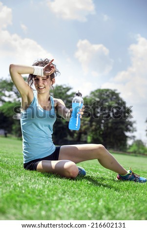 Tired woman runner taking a rest after run, drinking water