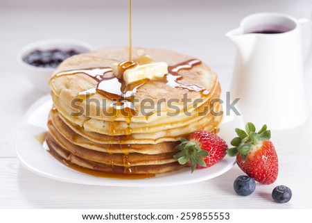 Delicious sweet American pancakes on a plate with fresh fruits and addons.