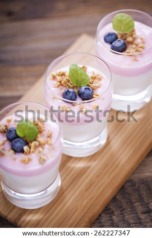 Delicious dessert, flakes flooded in two flavors yogurt with blueberries and fruit on a wooden board. dSLR photo