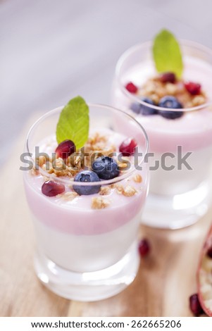 Delicious dessert, flakes flooded in two flavors yogurt with blueberries and fruit on a wooden board.