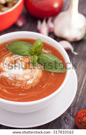 Delicious tomato soup with aromatic spices on a wooden table. Studio shot