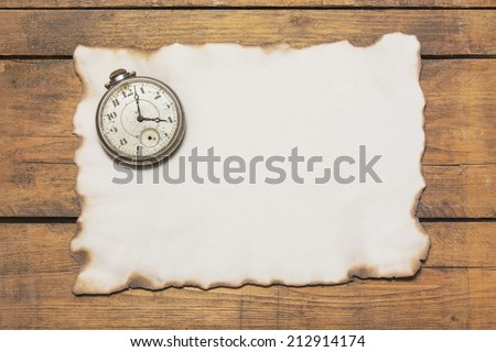 The old and broken pocket watch on the burnt paper