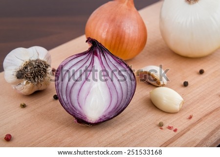 Red and white onion, garlic and spices on a wooden board