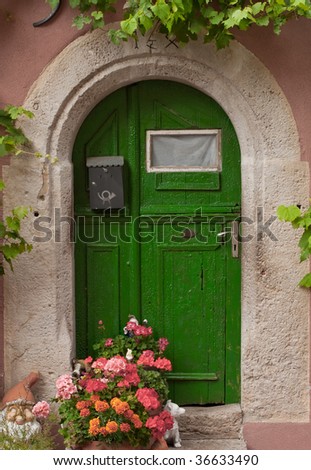 Green door in the form of the arch with flowers