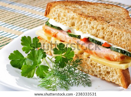 Sandwich with chicken cheese and vegetables on white plate