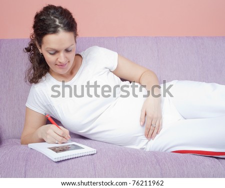 Pregnant woman holding her belly and writing nots