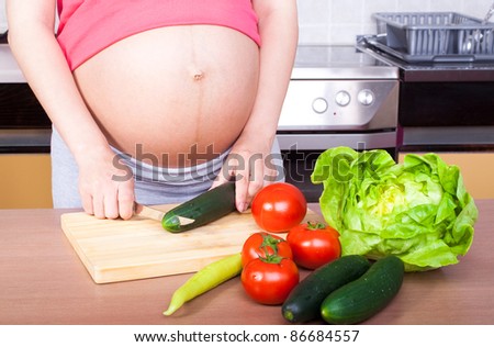 Pregnancy and nutrition - pregnant woman with vegetables on desk