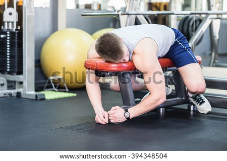 Tired and desperate men at the gym. Male athlete lying on a bench, exhausted.